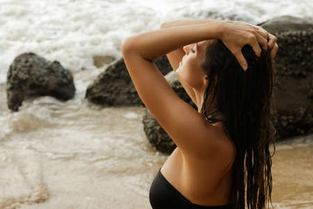 Sexy woman with wet hair on the rocky beachの写真素材