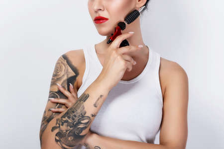 Young woman tattooist with a tattoo-machine in her hand on white backgroundの写真素材
