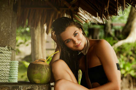 Happy woman is enjoying coconut drink in the old beach barの写真素材
