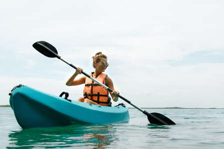 Happy young and beautiful woman kayaking in on the lakeの写真素材