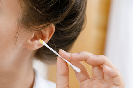 Woman is cleaning ear with a cotton swab