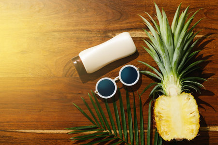 Different items for beach vacations. Sunscreen, sunglasses and pineapple fruitの写真素材