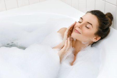 Young and beautiful woman is relaxing in the bath with a foam