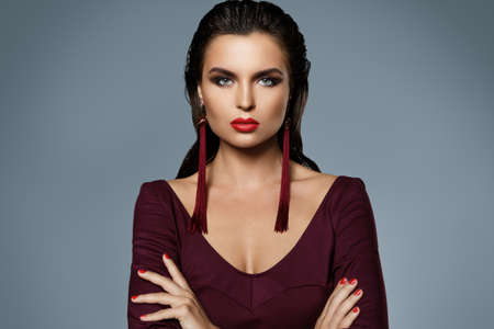 Portrait of stunning woman with a beautiful makeup wearing long red earringsの写真素材