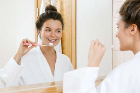 Woman cleaning her teeth in the bathroomの写真素材