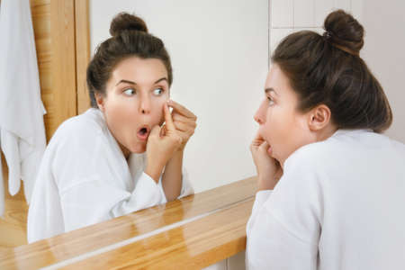 Woman squeeze pimples in the bathroomの写真素材
