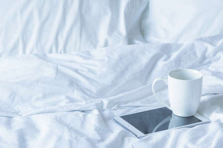 Good morning - Tablet pc and cup of coffee on the bedの写真素材