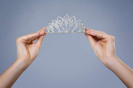Shining diadem in female hands isolted on gray backgroundの写真素材
