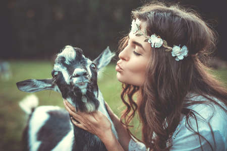 Young and beautiful woman with a funny friendly goat in the villageの写真素材