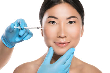 Asian woman is receiving facial injections. Isolated on white backgroundの写真素材