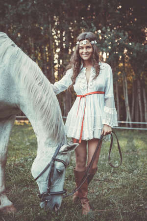 Young woman in beautiful white dress and her beautiful horseの写真素材