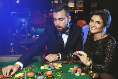Beautiful and well dressed couple playing roulette in the casinoの写真素材