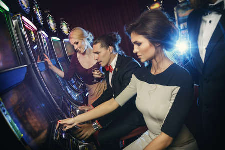 Group of friends playing slot machines in the casinoの写真素材