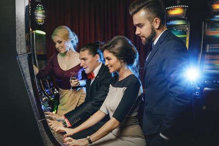 Group of friends playing slot machines in the casinoの写真素材