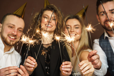 Party people with burning sparklers celebrating  holiday or event. Camera focus on sparklers.