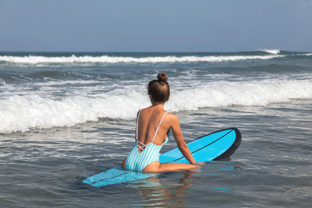 Young woman surfer is trying to catch the wave