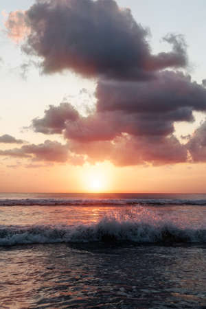 Sunset on the beach. Scenic seascape with clouds, waves and sun.の写真素材