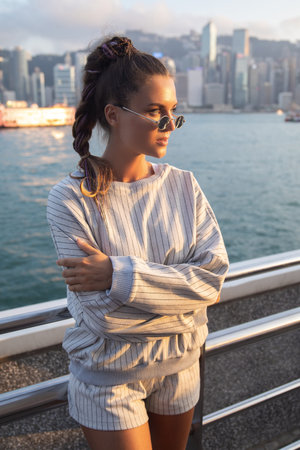 Stylish woman is posing in the Victoria Harbour, Hong Kong city.