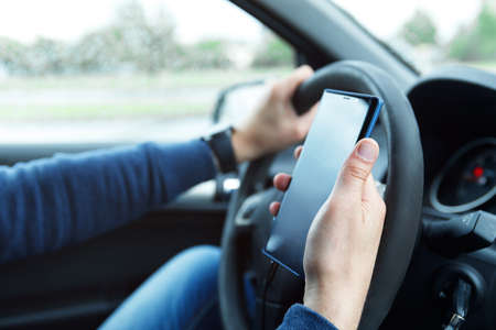 Male hands with phone. Man in car is using smartphone.の写真素材