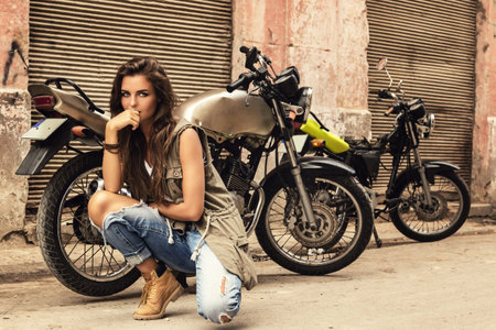 Woman model is posing beside old motorcycles