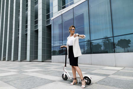 Young and beautiful businesswoman rides electric scooterの写真素材