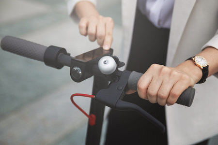 Female hands and steering wheel of electric scooter