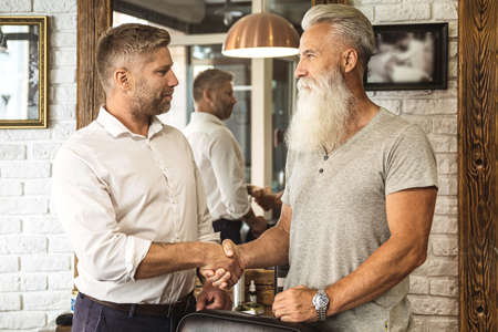 Happy hairdresser and client in the barbershopの写真素材