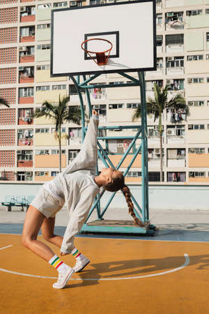 Young stylish woman is posing on the Choi Hung Estate Basketball Courtの写真素材