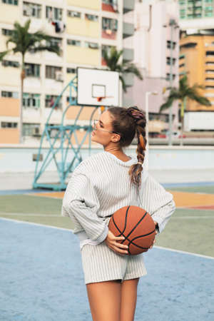 Young stylish woman is posing on the Choi Hung Estate Basketball Courtの写真素材