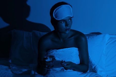 Woman in the bedroom with a glass of water and sleeping pills