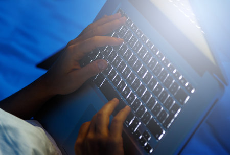 Female hands on the laptop computer keyboard at the night time
