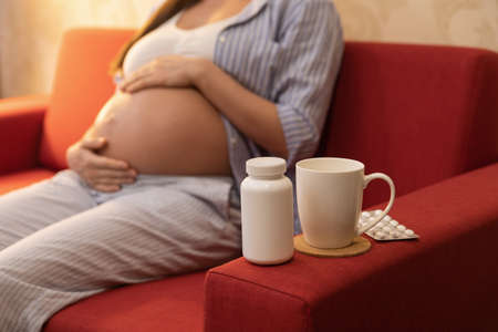 Pregnant woman and different pills at homeの写真素材