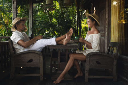 Young couple sitting on the terrace and drinking coffee or teaの写真素材