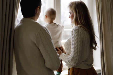 Young family at home is looking out the windowの写真素材