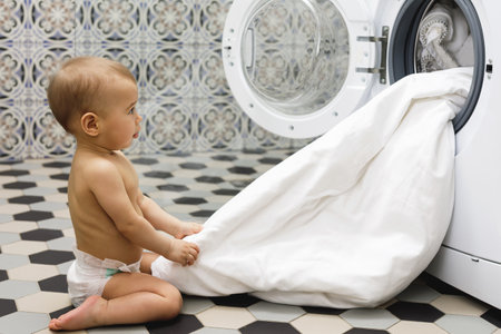 Cute baby boy beside the washing machineの写真素材