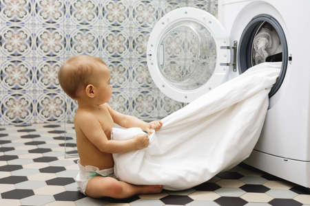 Cute baby boy beside the washing machineの写真素材