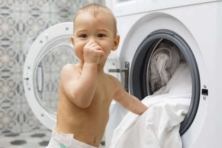 Cute baby boy beside the washing machineの写真素材