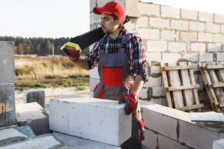 Bricklayer man is sawing autoclaved concrete blocksの写真素材
