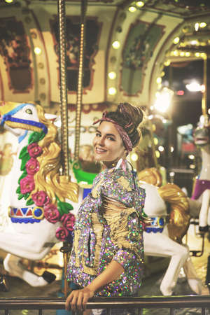 Stylish woman wearing sparkling jacket on the carouselの写真素材