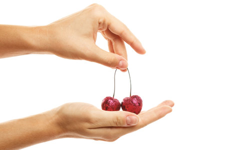 Female hands and cherry berries covered with a colorful glitters