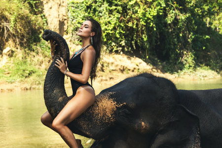 Happy woman is bathing with the elephant in the riverの写真素材