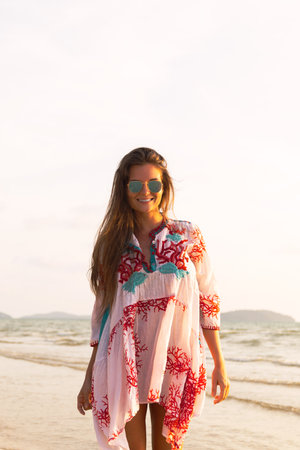 Young lovely woman wearing beautiful dress is walking by the sea shoreの写真素材