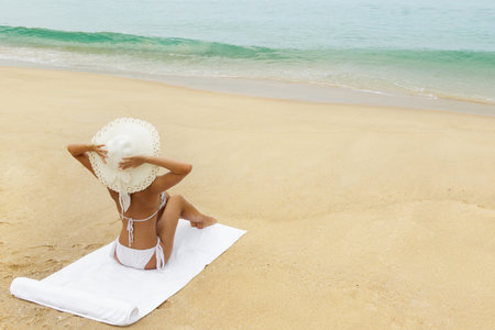 Woman in hat sitting on the beach