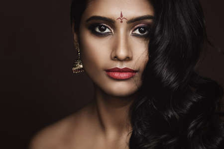 Portrait of Indian woman with beautiful makeup and hairstyle on brown backgroundの写真素材