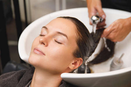 Woman in hairdresser salon during hair wash after haircutの写真素材