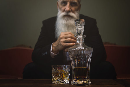 Handsome and bearded senior man drinking whiskey