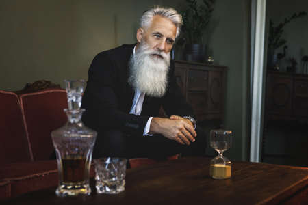 Handsome and bearded senior man drinking whiskeyの写真素材