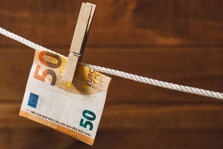 Euro banknote is hung on a rope with clothespinの写真素材