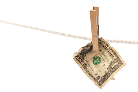 Crumpled US dollar banknote is hung on a rope with clothespinの写真素材