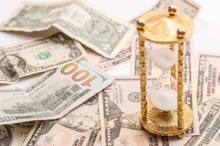 Hourglass and US dollar banknotes. Concept of investment and inflation.